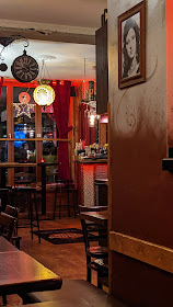 View inside a brightly painted restaurant with hanging lights and a vintage painting on the wall.