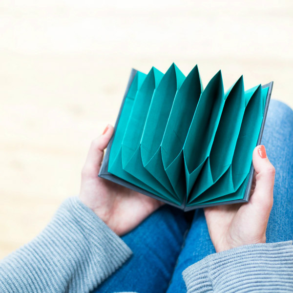 hands displaying teal colored paper ori-folder book