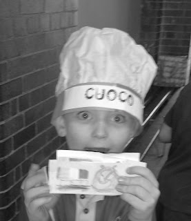 Black and white photo of young boy with money and a chef's hat