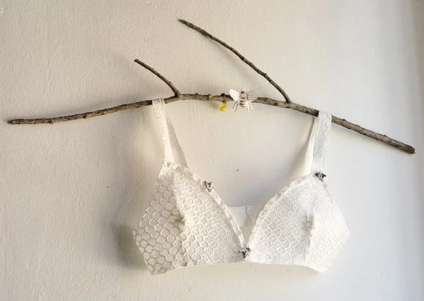handmade honeycomb paper bra with bees displayed on natural stick