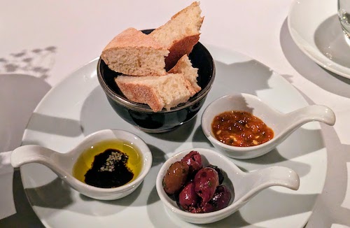 Bread served with olive oil, olives, and harissa