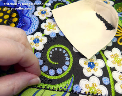 Embroidering the black beaded background with black beads and also showing the bead holder with the beads. (Wild Child Japanese Bead Embroidery by Mary Alice Sinton)