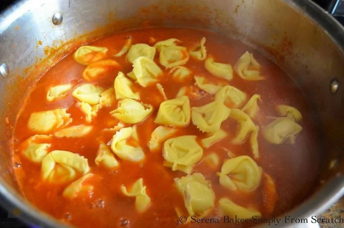 Tomato Soup with Cheesy Tortellini added in a stainless steel soup pot.