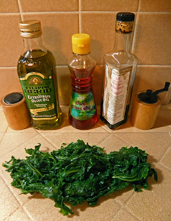 Cooked Kale with Bottles of Balsamic, Olive Oil, Salt, Pepper, and Hot Chili Oil