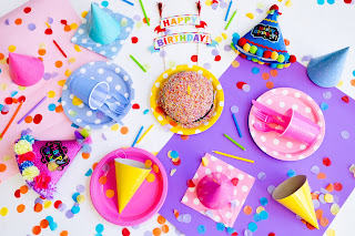 assorted party items (hats, confetti, cupcakes) on a white background 