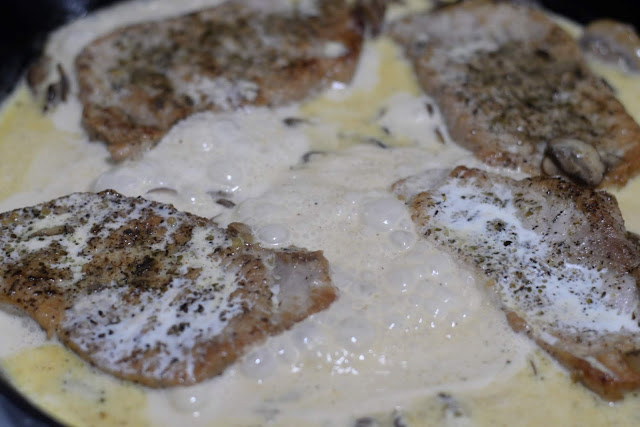 The cream sauce simmering in the pan with the pork chops. 