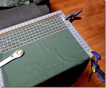 Fabric with cutting guides clamped to table with woodworking clamps.