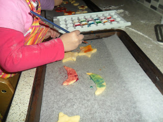 Child painting biscuit dough shapes.