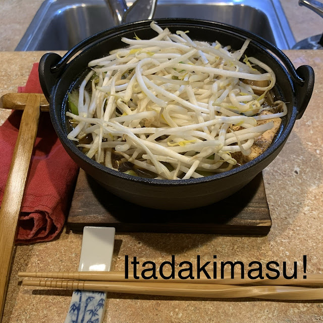 iron pot at place setting with spoon, napkin, and chopsticks