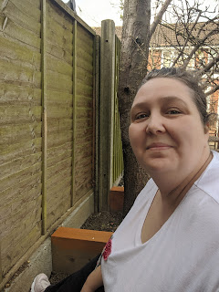 Pippa D sitting in a raised bed  painting the woodwork