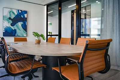 an empty conference room; tan chairs around a white table with some abstract art on the wall