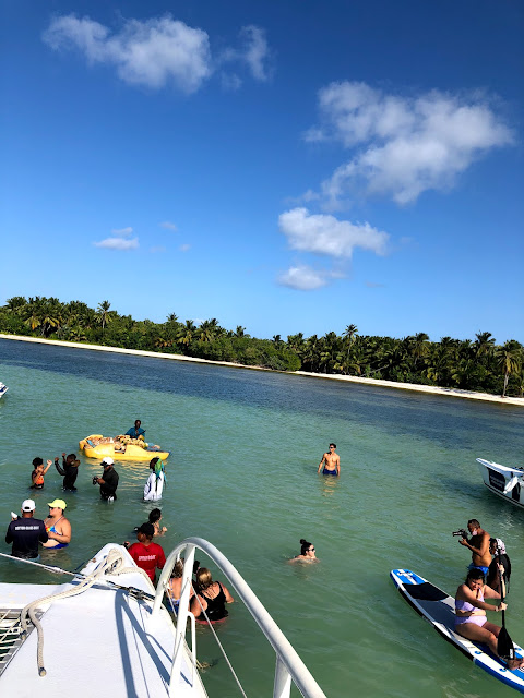 A large bay with numerous people standing in the chest height water,