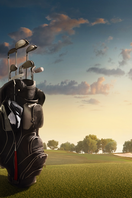 Sunrise on a golf course with a bag full of clubs in the foreground.