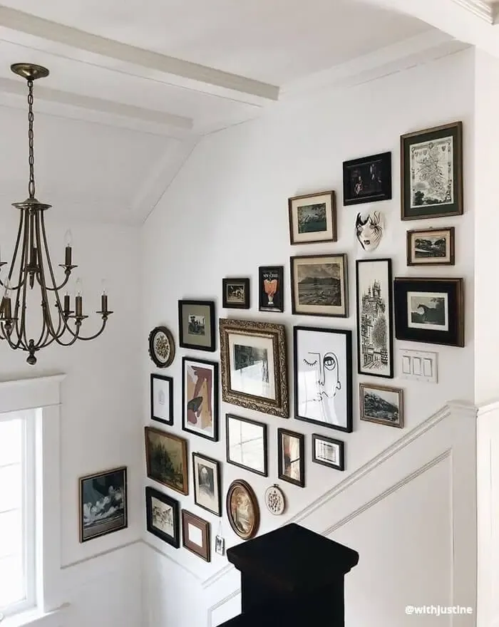 Black and white frames and pictures hung on a white wall in stairway