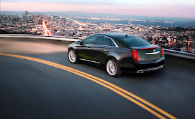 Black 2013 Cadillac XTS on curve above city at dusk