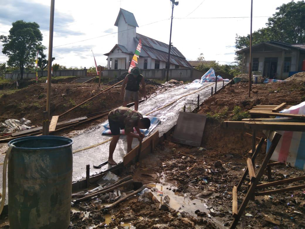 Anggota Satgas TMMD Membuka Papan Mal Jalan Rabat Beton Pustu