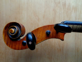 close-up photo of the scroll and pegs of a 19th century violin