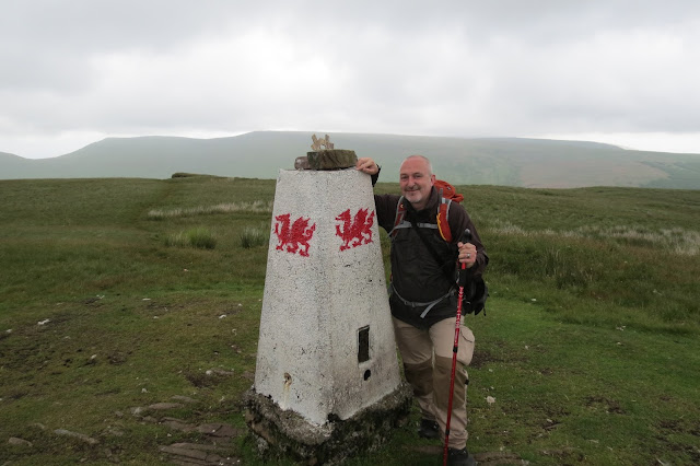 Me by an OS trig pillar, which is painted white and emblazoned with a red Welsh dragon on each face.