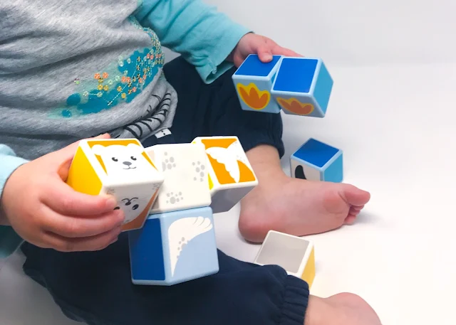 A close up shot of a toddler playing with magnetic cubes with pictures on
