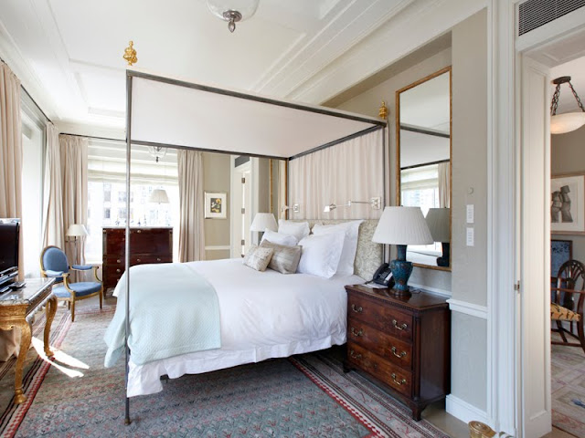 master bedroom with four poster bed, large windows with floor length curtains, gray walls with white trimming and a large area rug