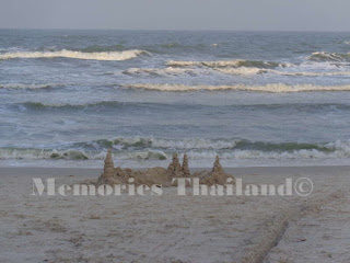 The calm sea of Hua Hin beach with a handmade sandcastle in the foreground