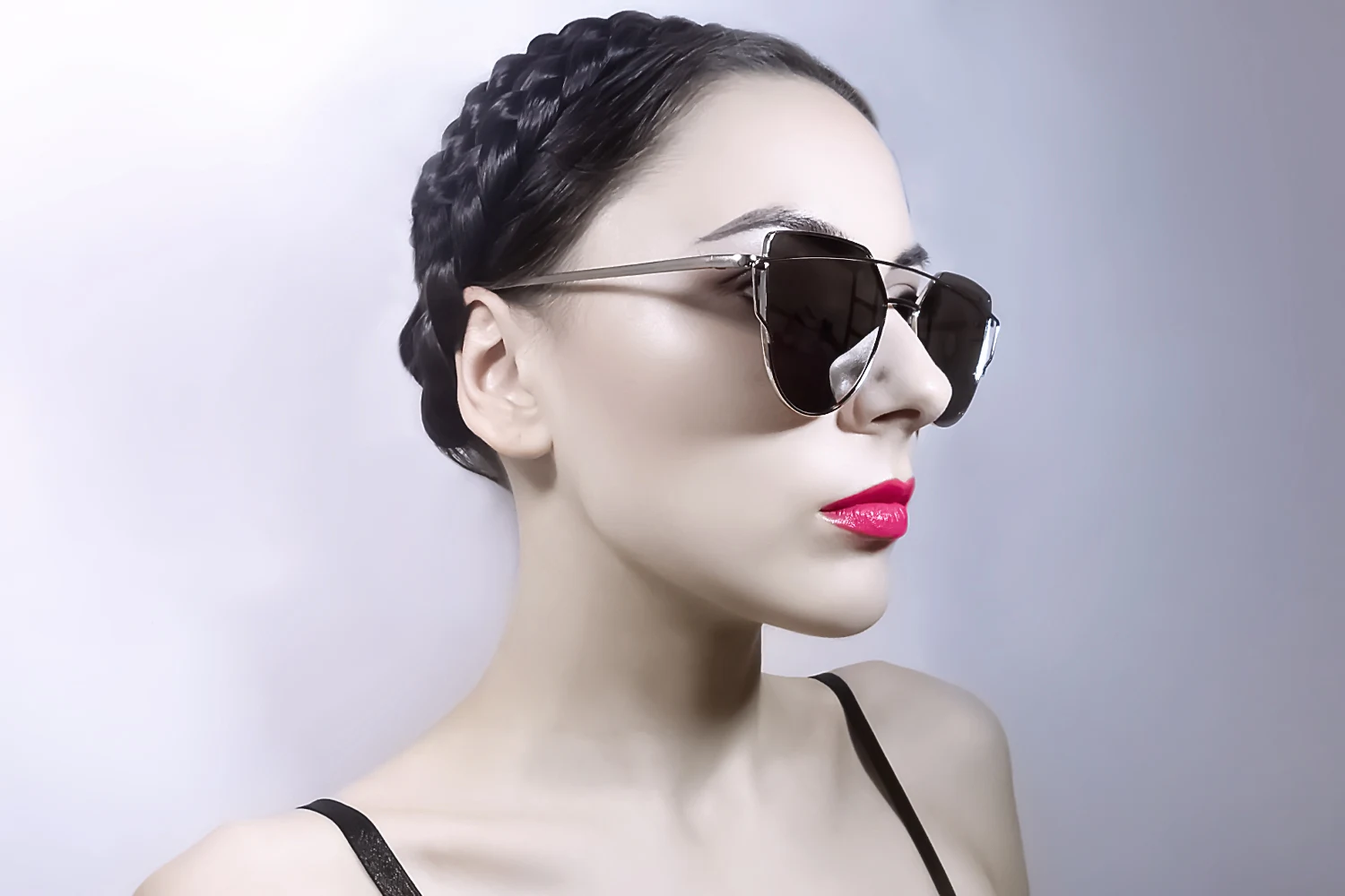 woman on a plain background with updo hairstyle is wearing and oversized mirrored, aviator sunglasses