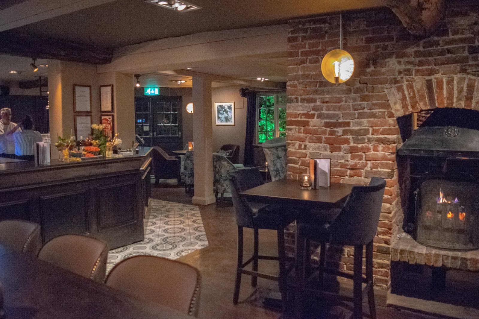 A overview of the inside of the pub at The Red Lion. There is the bar on the left and high stool seating and the a sofa and armchair seating area to the right.