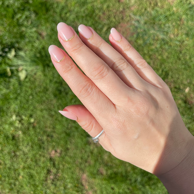 Glamnetic press on nails after application on female hand over grass, in the sun