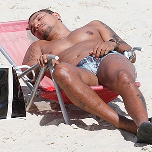 Naldo Benny de cueca e sem camisa dormindo na praia exibindo corpão