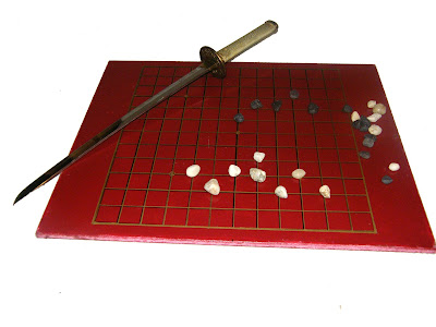 A Go game board with a samurai sword laying across a corner.