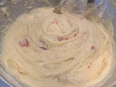 Raspberry muffin batter in a silver mixing bowl