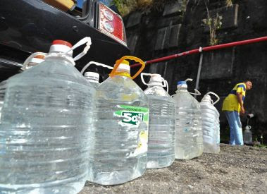 Bountiful trip: A man filling up a few bottles of the water from the hill slope.