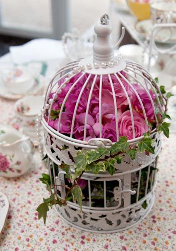 Vintage style bird cage decorated with fresh flowers and ivy trails 