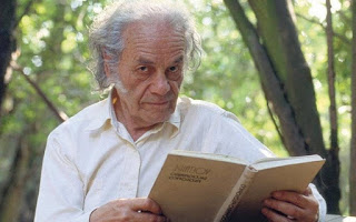 El poeta chileno NIcanor Parra conun libro en las manos y árboles difuminados de fondo