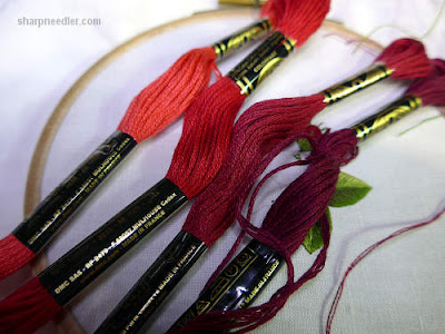 Four shades of red thread that will be used to stitch the petals on a needle painted rose