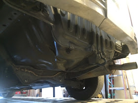 Looking at underside of car after bumper cover removed. There are large dents in floor and rear panel.