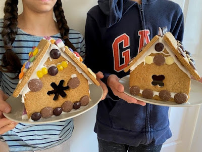 Two children holding their gingerbread houses