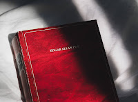 Close up photo of a red book with Edgar Allen Poe on the front which is partially lit and partially in shadow