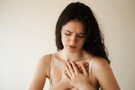 A lady feeling heart pain keeping her hands on her heart