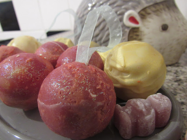 White Chocolate Baubles filled with Cointreau milk chocolate ganache. Half glittery pink, half gold.