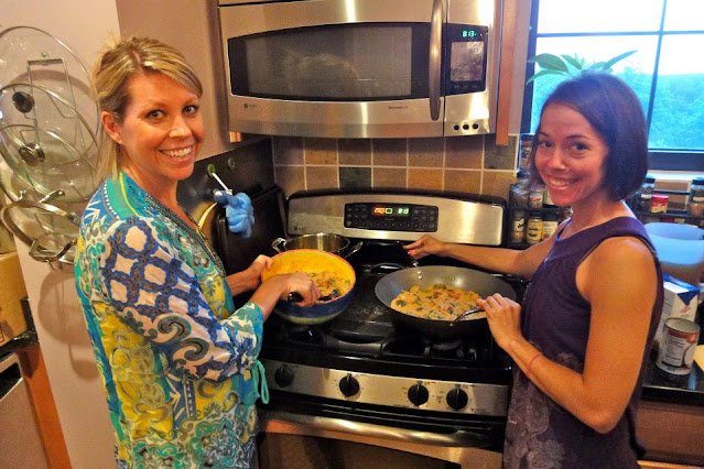 Two women in front of stove posing for a picture while making Thai Red Curry chicken