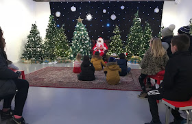 Father Christmas sitting telling festive tales with lots of Christmas trees 