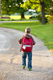 child going school with backpack in garden