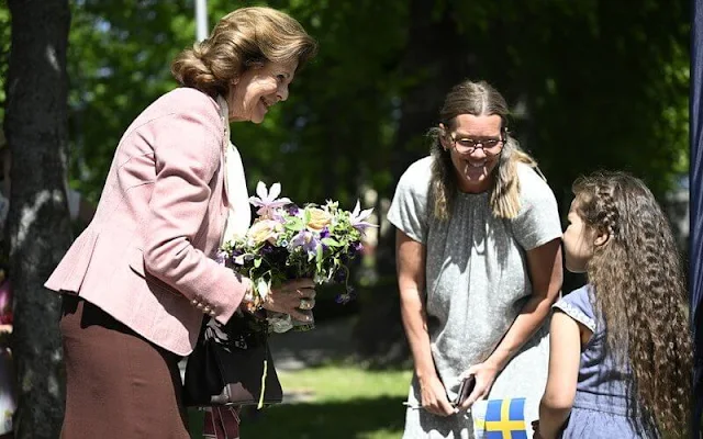 The King and Queen visited the House of Emigrants in Vaxjo. Queen Silvia wore a pink blazer and black skirt