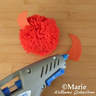 Red pom pom with a glue gun sticking on pieces of craft foam