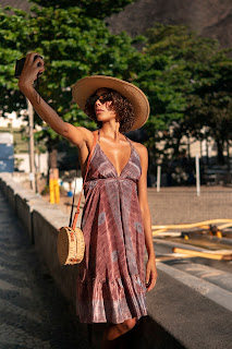 "Mulher sorrindo em um cenário de verão, vestindo um look vibrante e colorido, capturada com luz natural."
