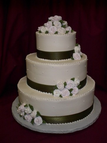  small sugar roses on elegant three tier round white wedding cake