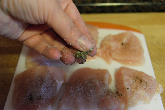 The chicken being seasoned with pepper.