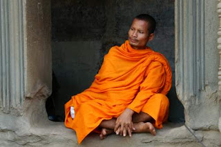 Image of a Buddhist monk sitting under a lintel in Angkor Wat