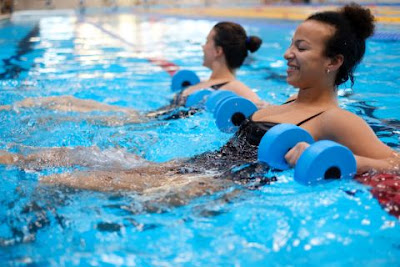 Picture of happy women laying in the pool with float bells exercisiing.